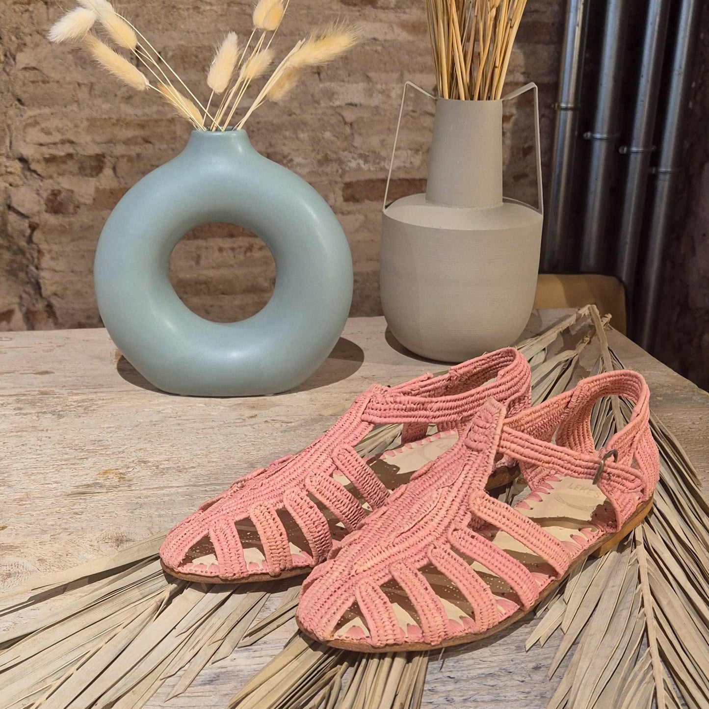 Cangrejera Hana en tono rosa empolvado sobre hojas de palmera secas 